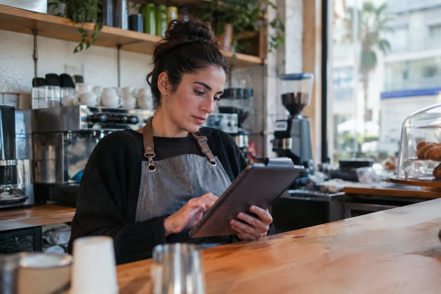 A small business owner reviews the quality of her marketing videos on a tablet in her cafe.