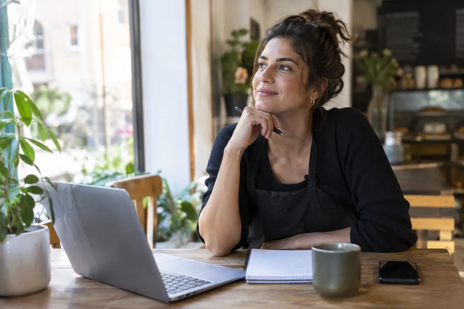 A small business owner sits at a desk, planning their social media content calendar on a laptop.