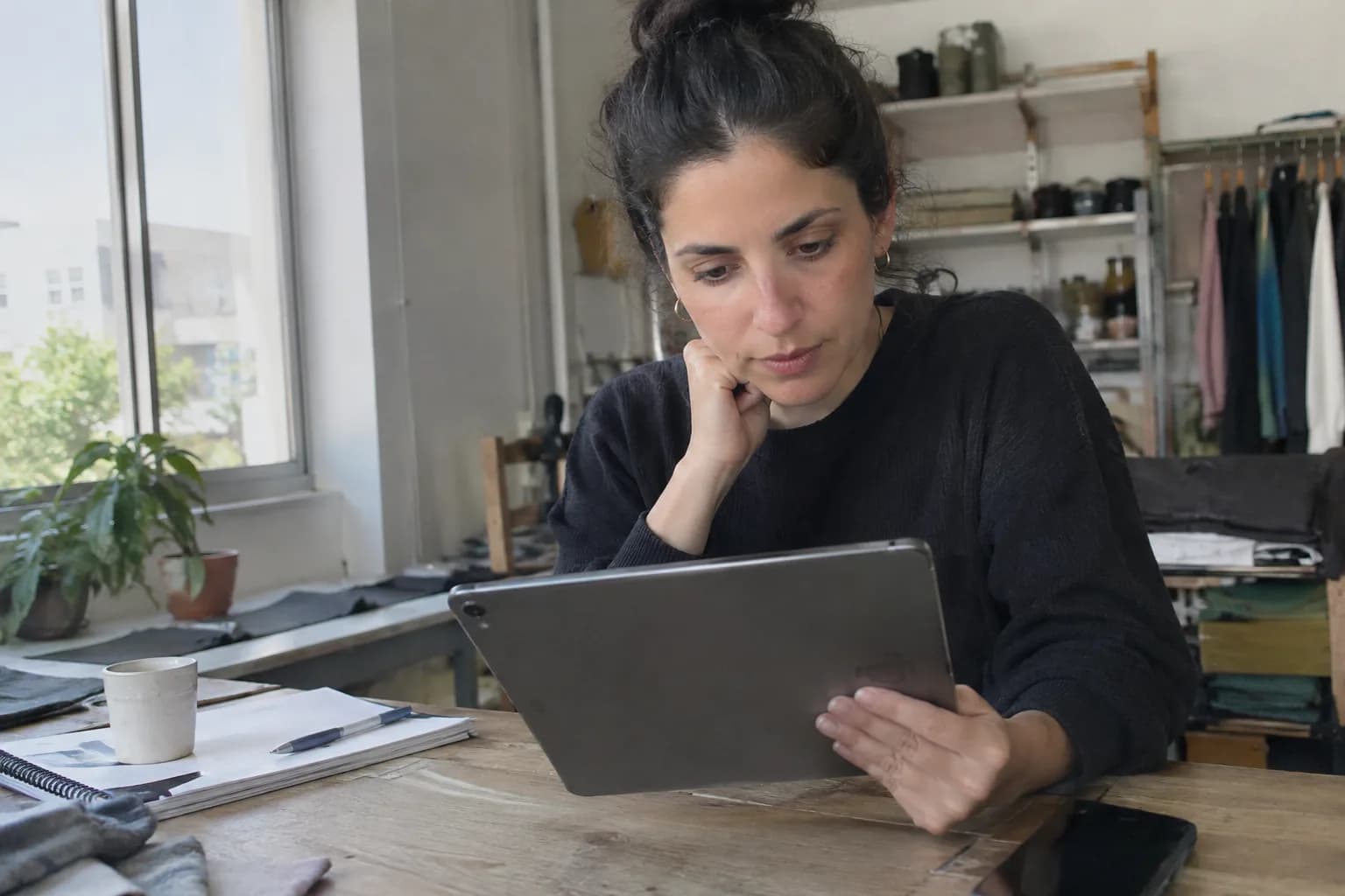 בעלת עסק קטן בוחנת דוגמאות למודעות וידאו ממומנות על טאבלט במשרד שלה.