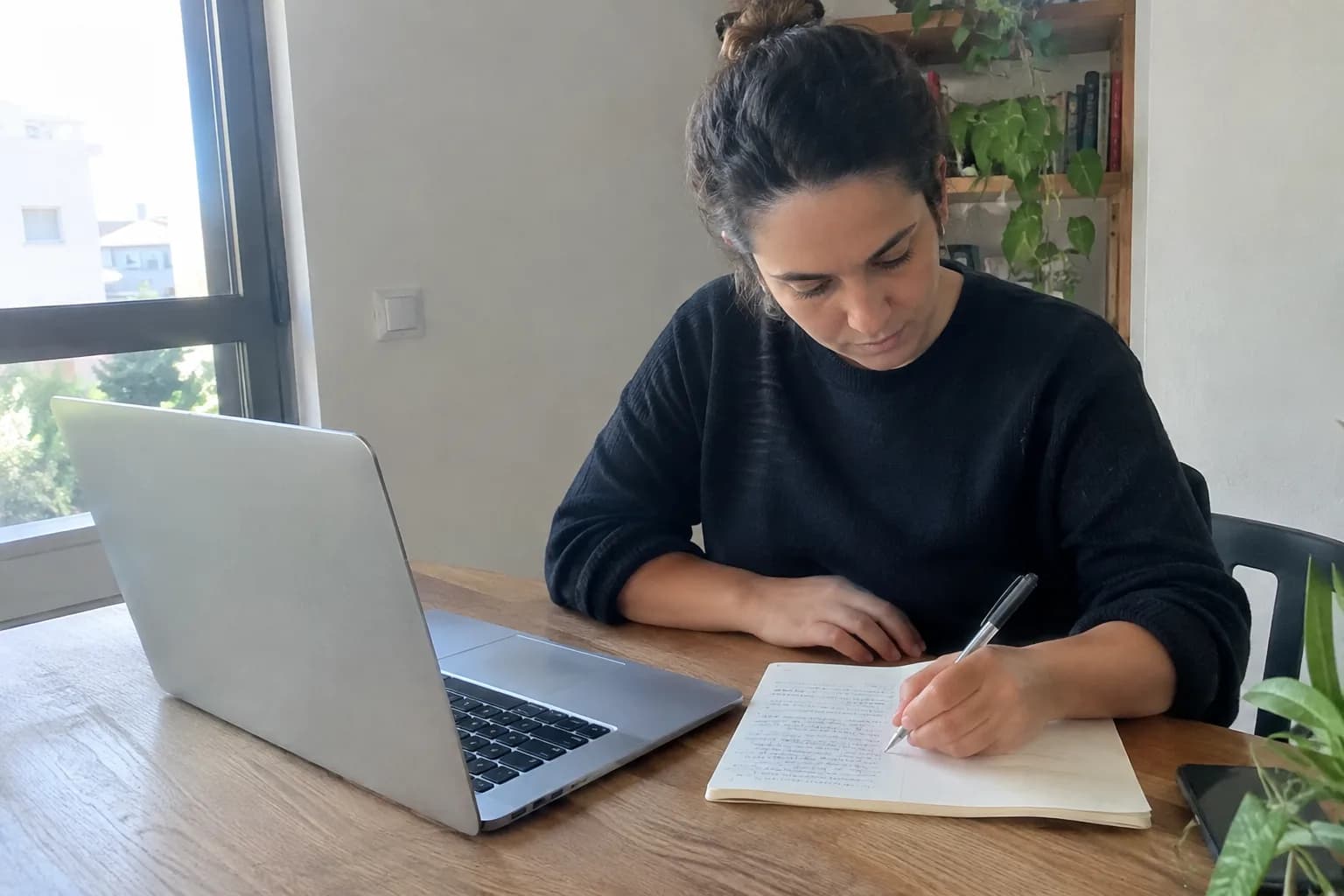 A small business owner plans and writes a script for a marketing video in her office.
